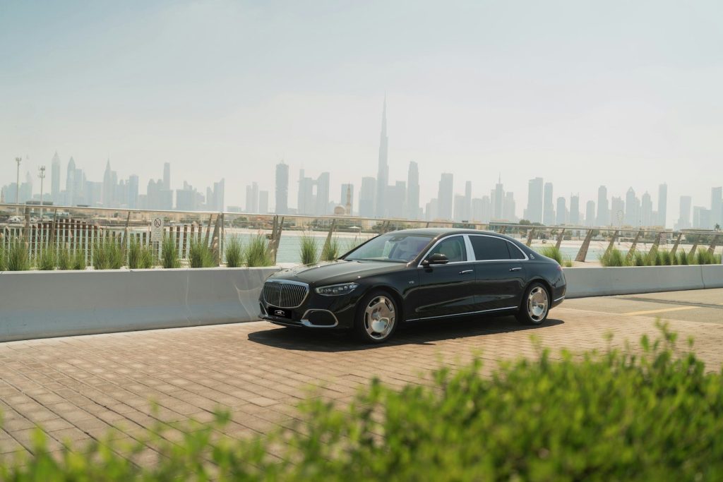 A black car driving down a road next to a city