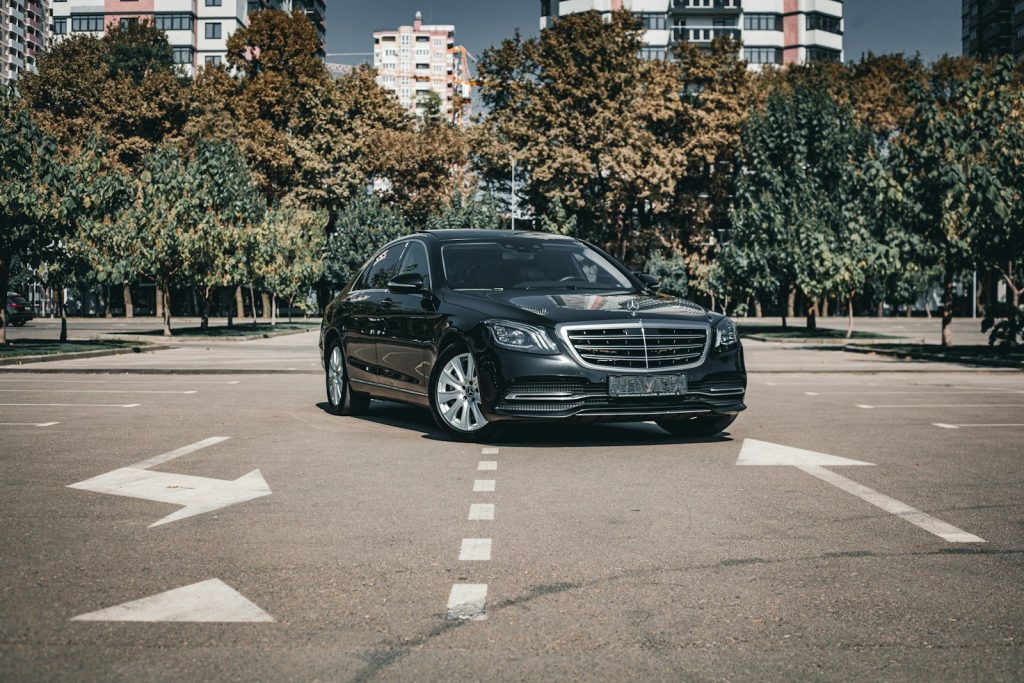 A black mercedes-benz car parked on asphalt with arrows.