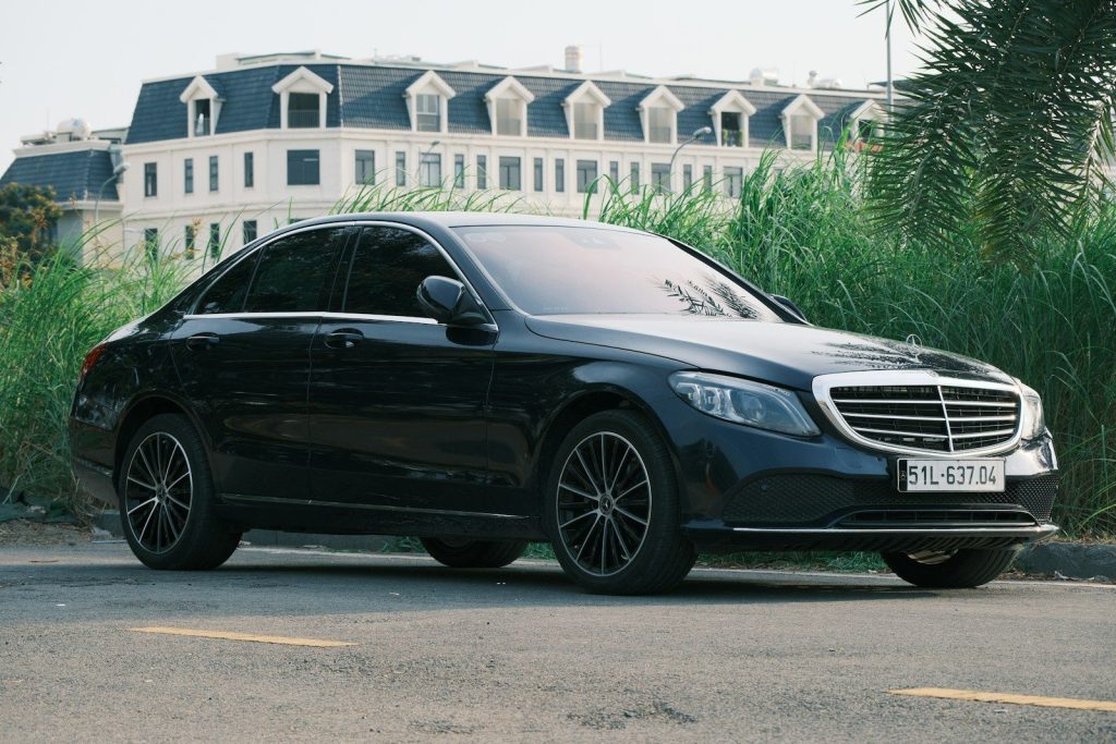 A black mercedes-benz is parked on the road.
