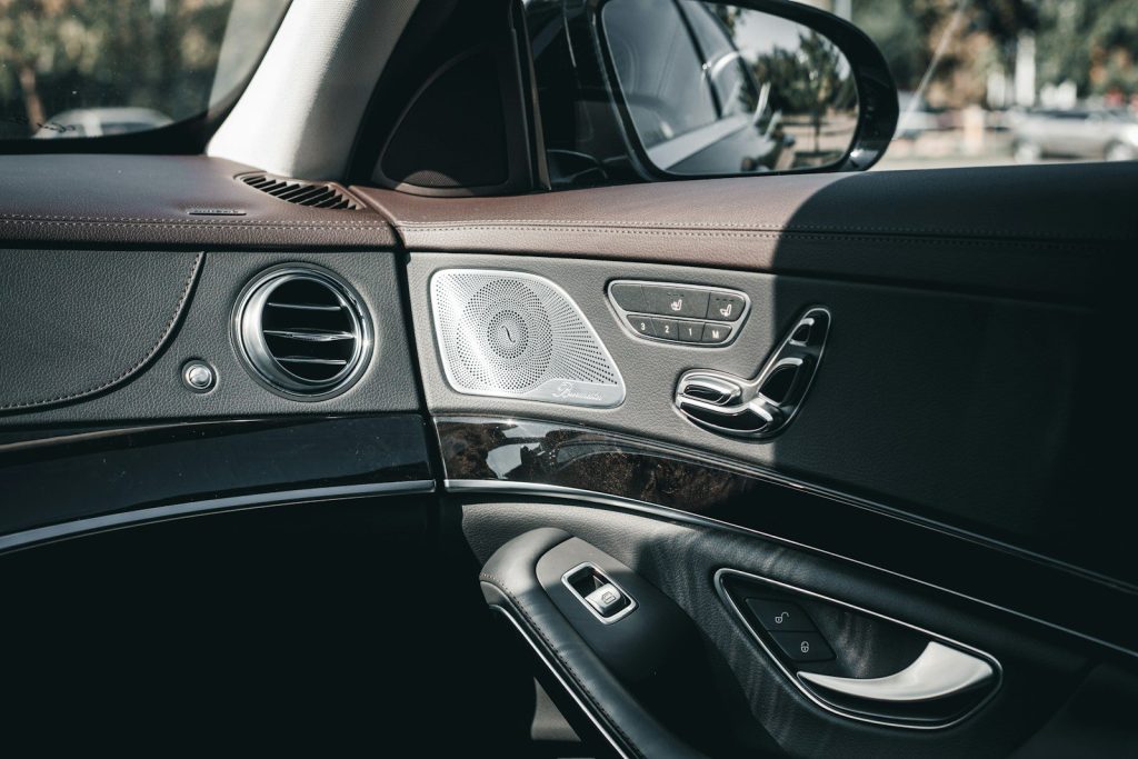 Luxury car interior with door controls, speaker, and air vent.